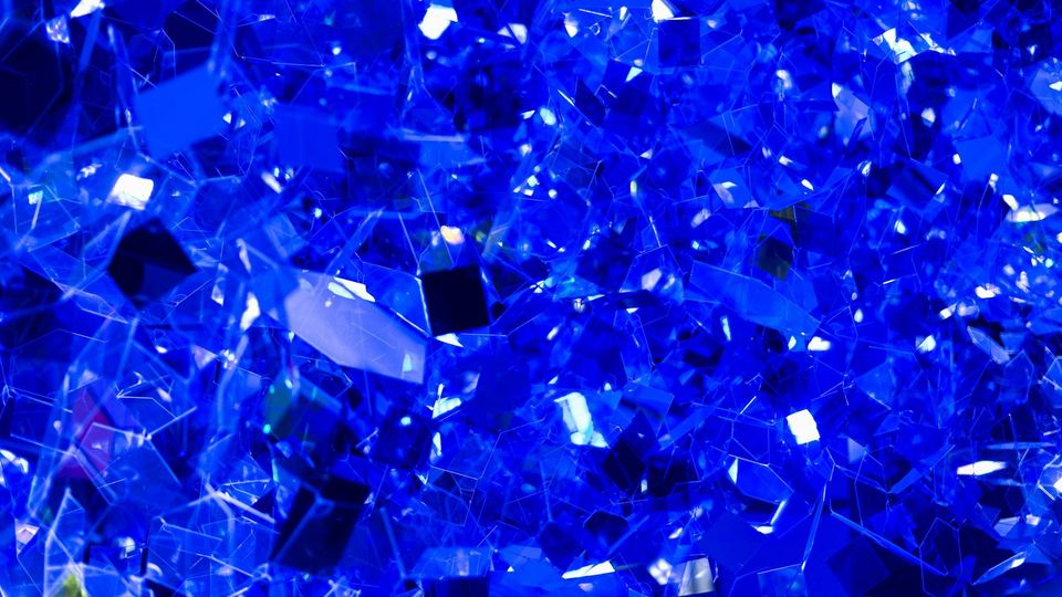 Blue crystal shards reflecting light with a faceted, abstract texture.