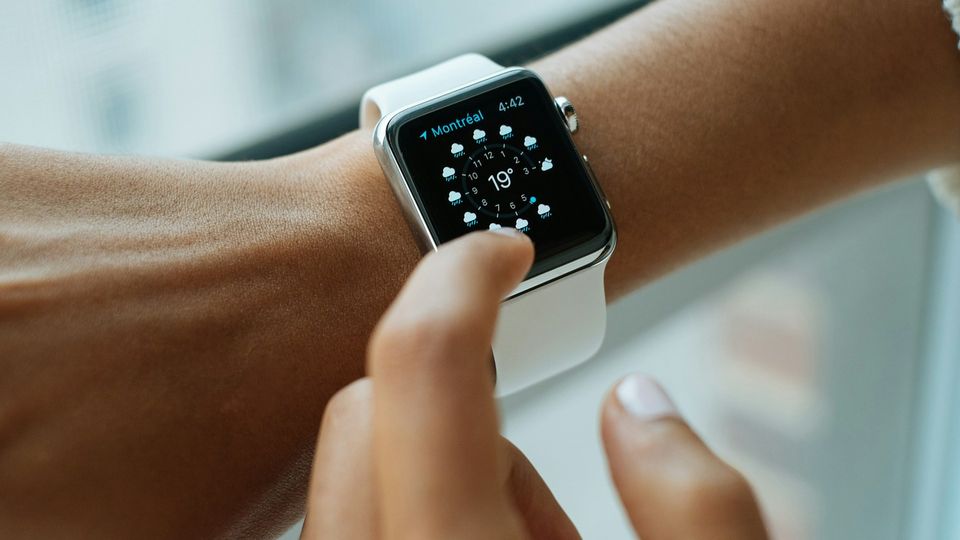 Person checking weather on a digital smartwatch with touchscreen interface.