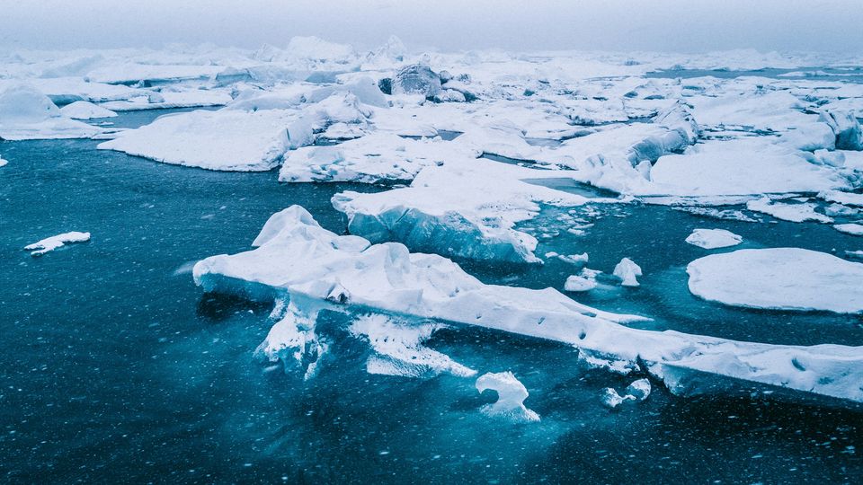Small ice sheets floating on dark blue Arctic waters.