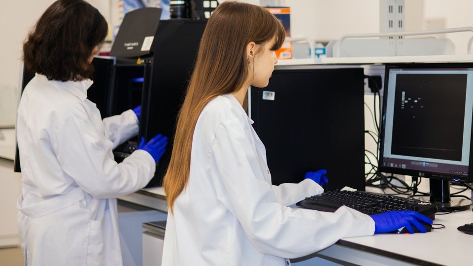 Researchers analyzing lab data on a computer screen in a modern laboratory.