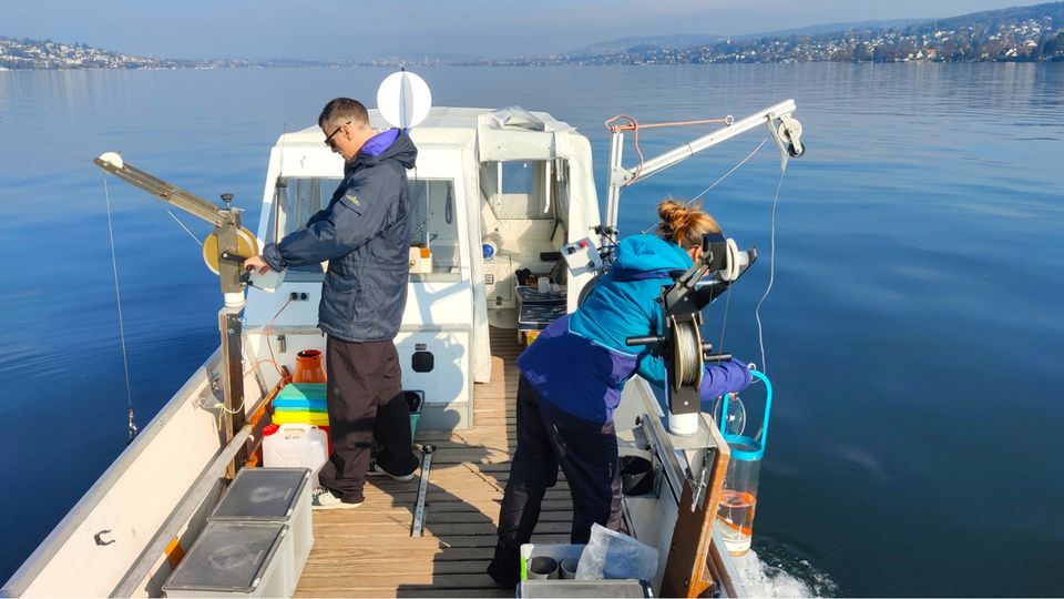 Researchers collecting water samples on a boat.