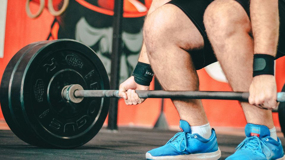 A man in a gym performing a deadlift with a heavy barbell.