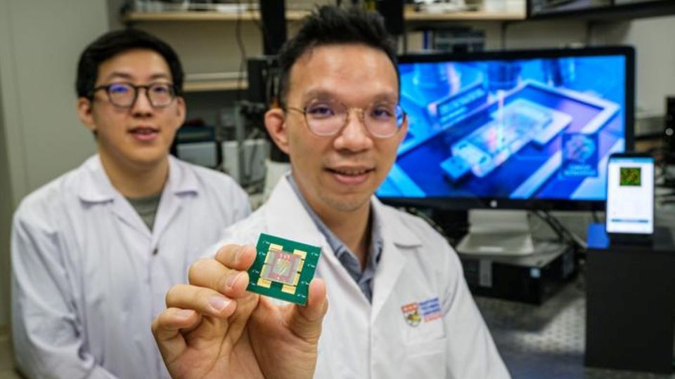Researcher holding a biochip in hand inside a laboratory setting.
