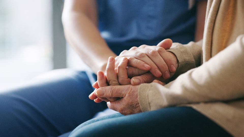 Two people holding hands in support, illustrating dementia care and emotional connection.