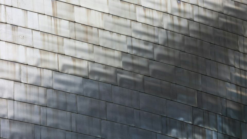 Weathered tiled wall with stains and shadows creating a textured pattern.