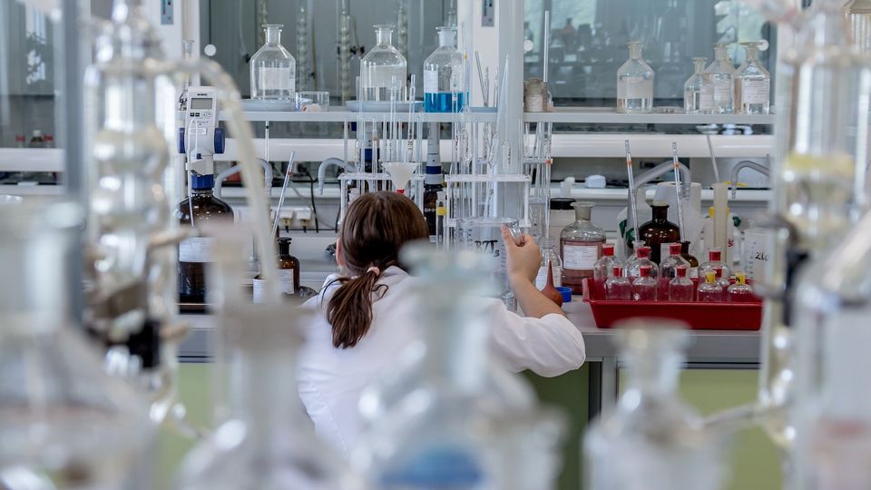 Researcher working in a laboratory surrounded by glassware and chemical samples.