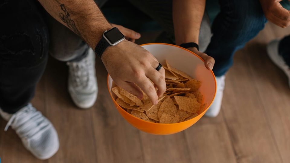 A man reaching into a large bowl of tortilla chips.