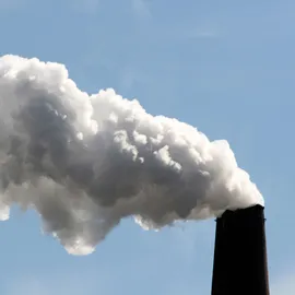 Industrial smokestack releasing thick white plume into blue sky, illustrating SPME geometries in air pollution analysis.