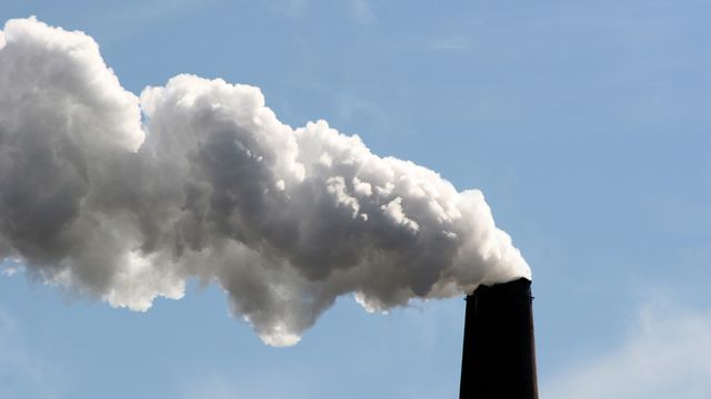 Industrial smokestack releasing thick white plume into blue sky, illustrating SPME geometries in air pollution analysis. 