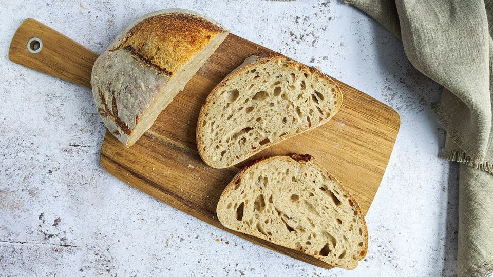 Sliced rustic bread loaf on a wooden cutting board with airy crumb texture.