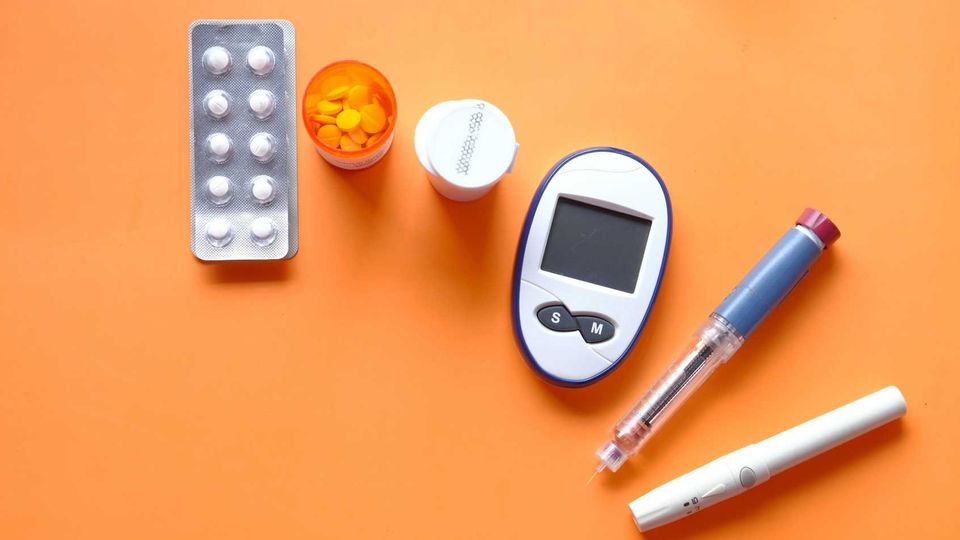 Blood sugar testing kit with glucometer, insulin pen, lancet, and pills.