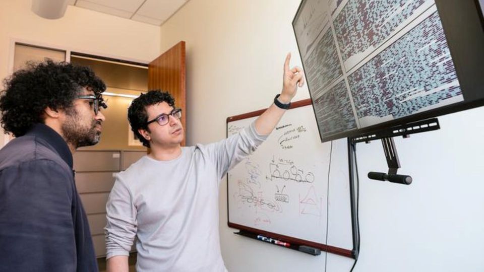 Researchers analyzing data on a large screen in a lab.