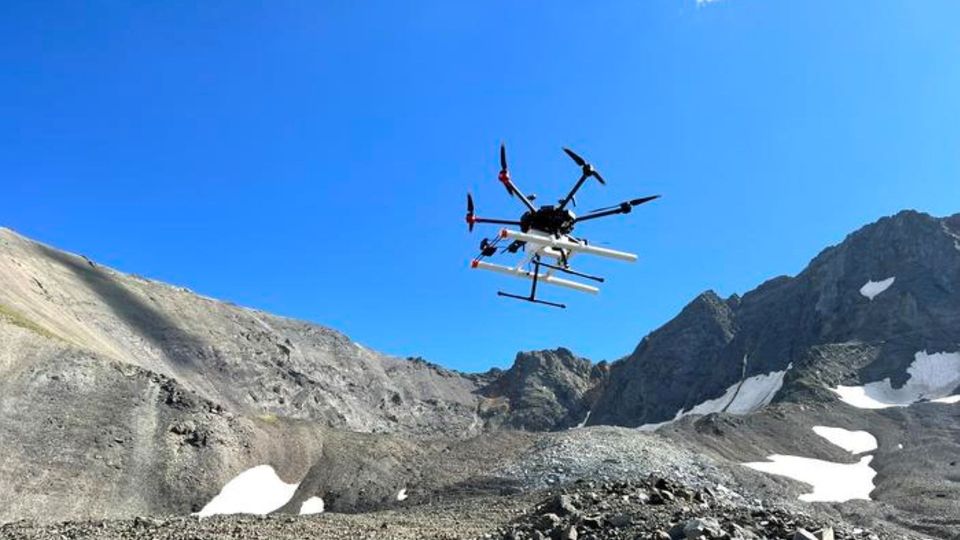 Drone flying over a rocky mountain landscape with patches of snow.