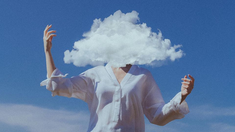 A woman flailing her arms, with her face covered by a white cloud, as she stands against a sky blue background.