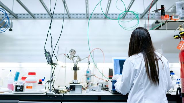 Researcher working at lab bench with scientific equipment and computer analysis setup. 