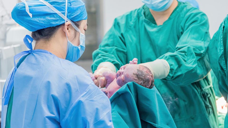 A doctor holds a newborn right after delivery.