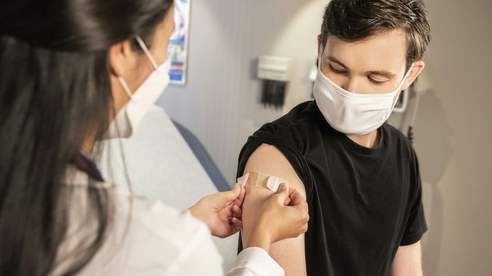 A health care provider places a bandage on the injection site of a patient.