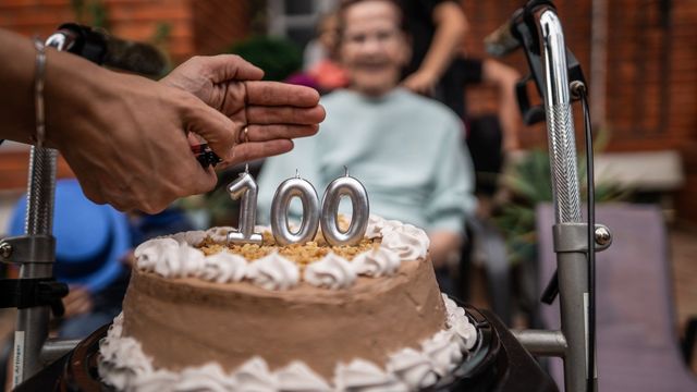 Birthday cake with “100” candles celebrating centenarians and healthy aging. 