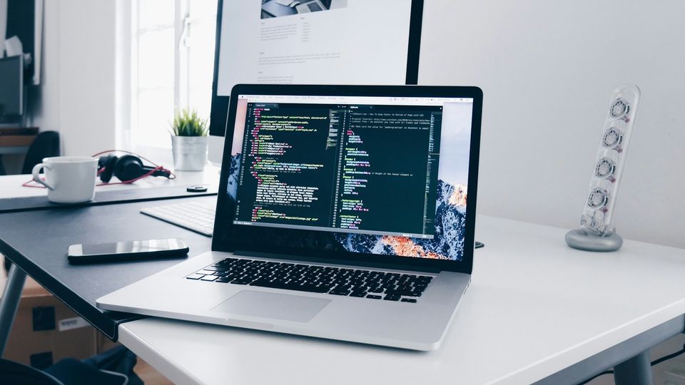 MacBook display showing software development code on a modern workspace desk setup.