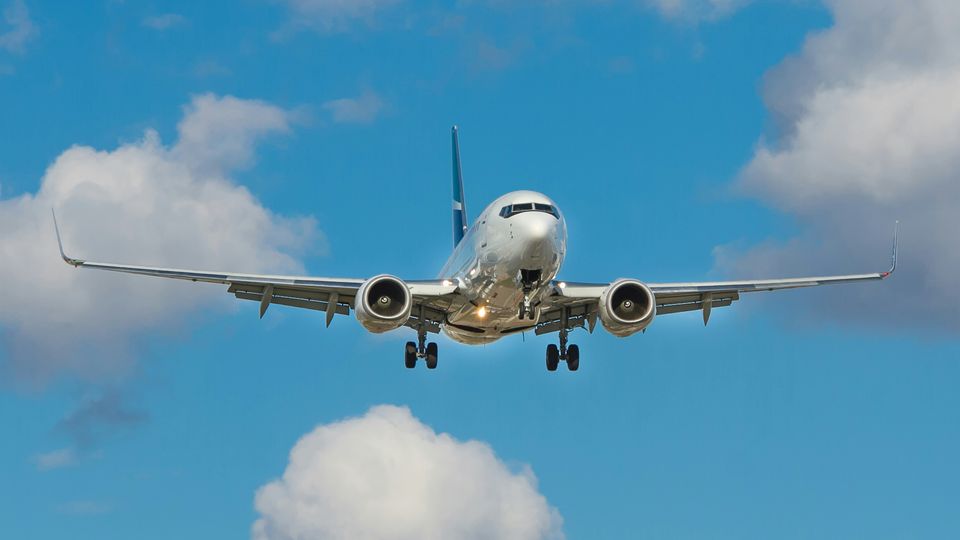 A silver airplane flying low among the clouds.