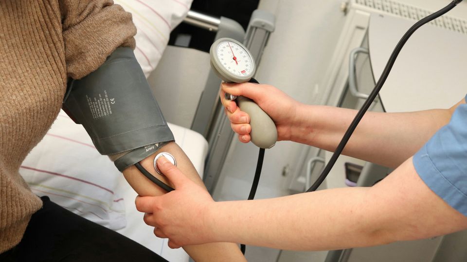 A nurse using an inflatable cuff to check a patient's blood pressure.