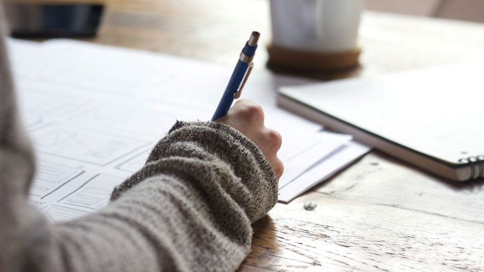 Person writing notes with a pen at a desk during work.