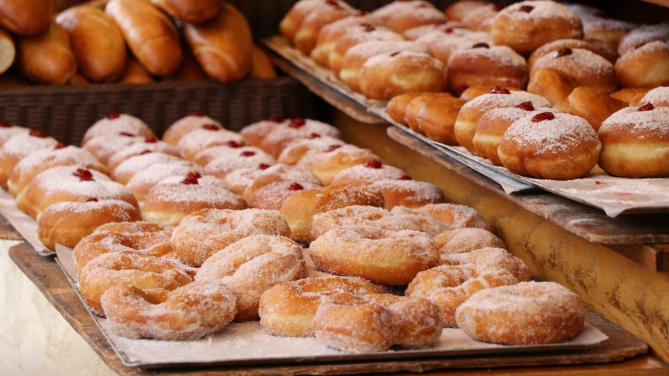 Trays of sugary donuts at the front of a bakery.