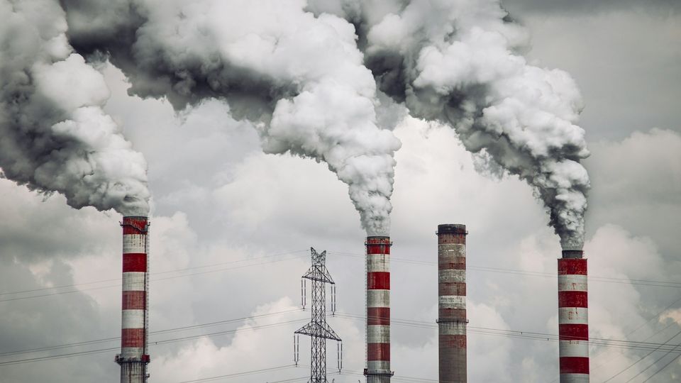 Factory smokestacks releasing thick industrial smoke into the atmosphere.