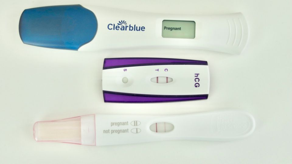 Positive pregnancy test devices showing hCG results with digital and line indicators on a white background.