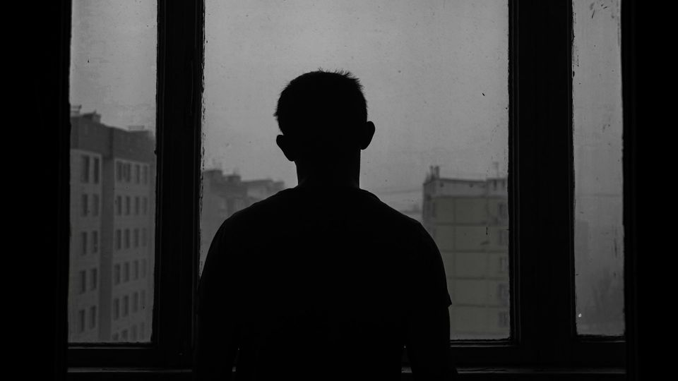 Silhouette of a man standing in front of a window in a dark room.