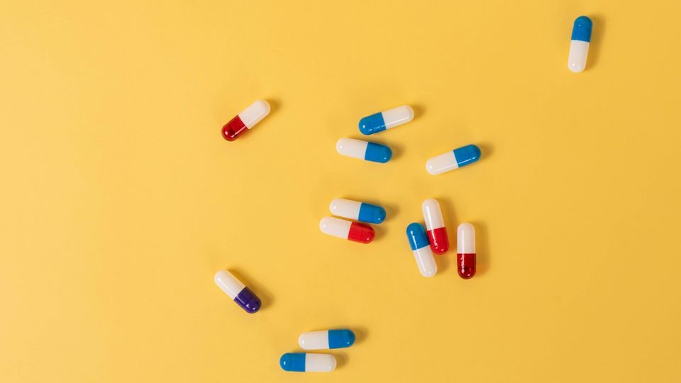 Birds-eye view of colorful capsules scattered across a yellow background.