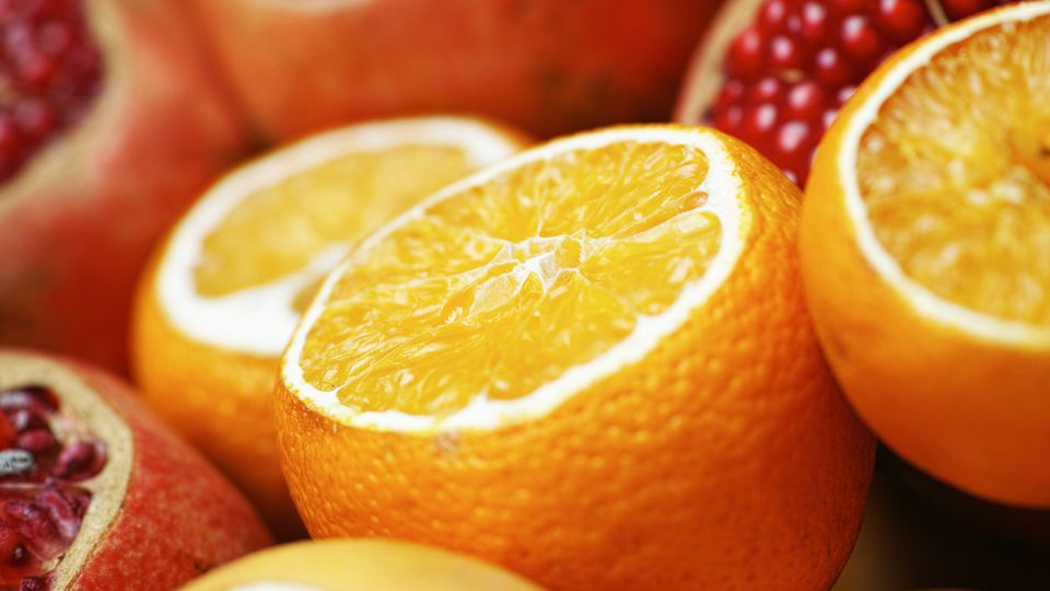 A pile of sliced oranges and pomegranates.