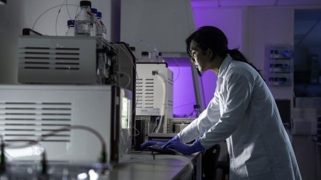 Researcher working in a laboratory with advanced scientific equipment and computer analysis. 