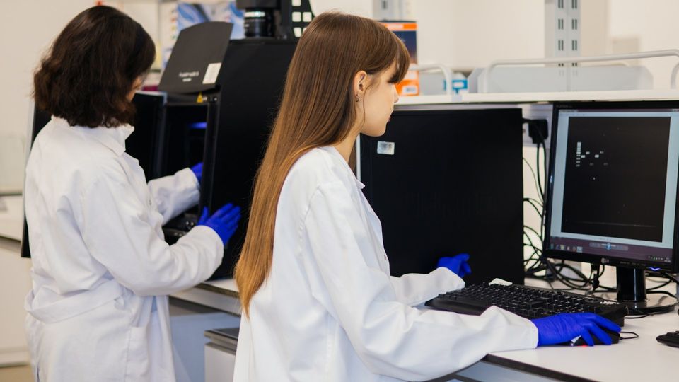 Researchers analyzing laboratory data on computer screens in a biomedical research lab.