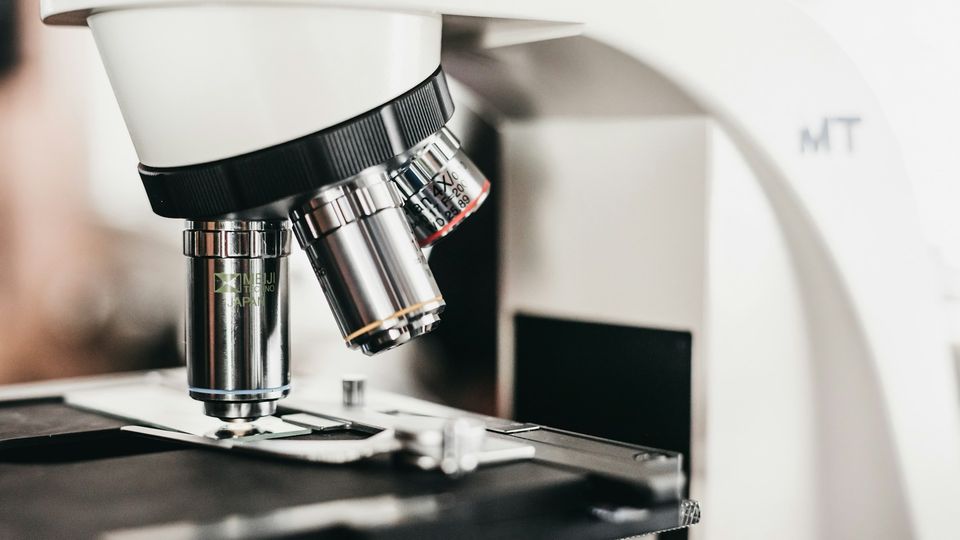 Close-up microscope objective lenses examining a specimen slide in a scientific research laboratory.