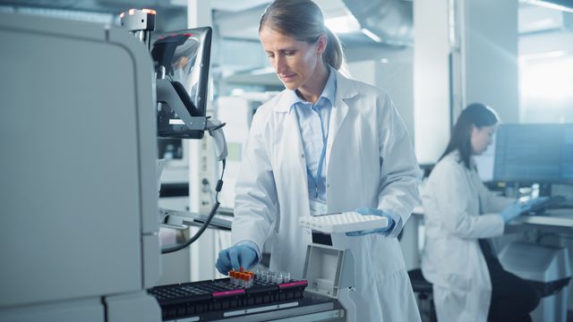 A scientist loading sample vials into a piece of analysis apparatus. 