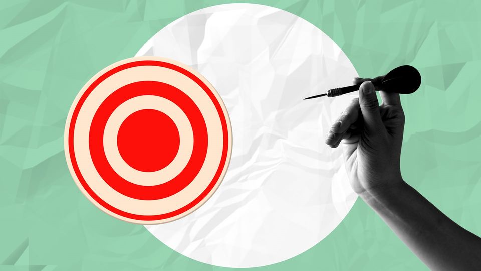 Collage style picture of a hand holding a dart beside a red target, set on a white and green background.