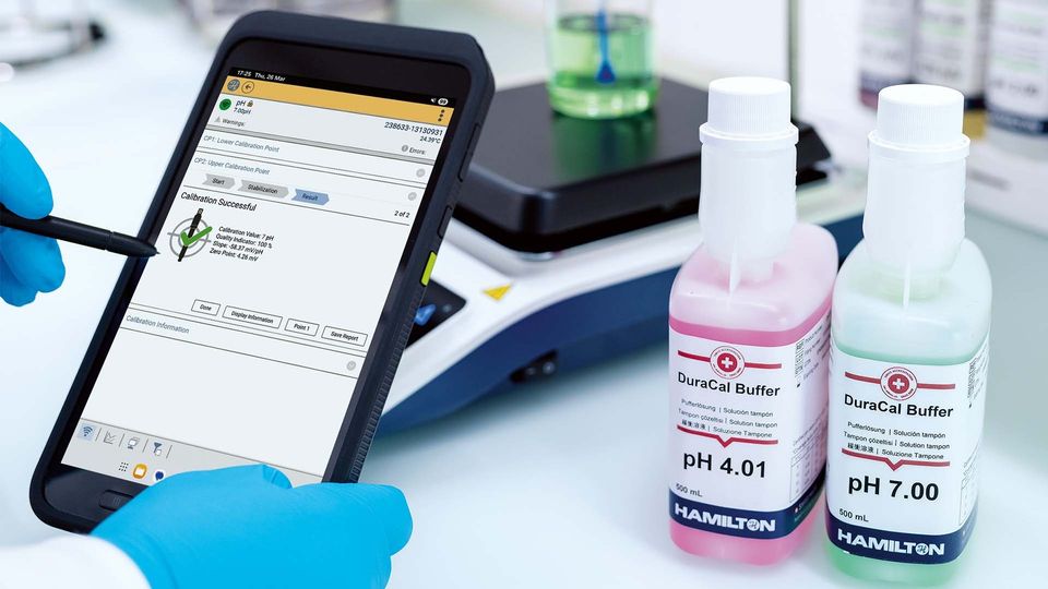 Laboratory technician using a digital meter to calibrate pH buffers with pH 4.01 and pH 7.00 solutions.