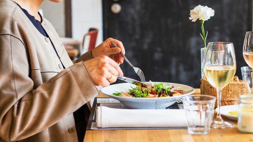 A woman at a restaurant eating a salad.