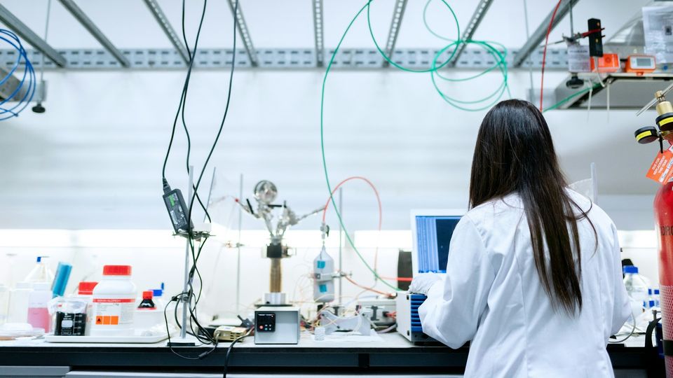 Researcher working at a laboratory workstation surrounded by scientific equipment and analytical instruments.