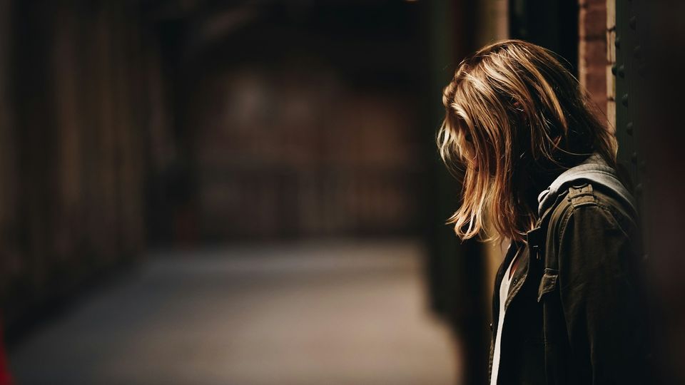 Girl standing alone in a dimly lit alleyway.