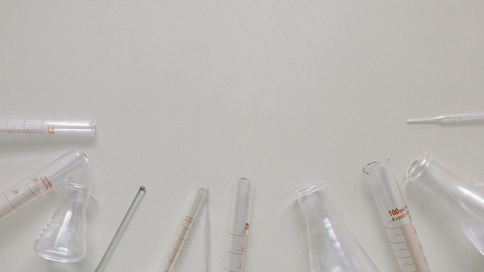 Laboratory glassware including beakers, flasks, graduated cylinders, and pipettes arranged on a clean surface.