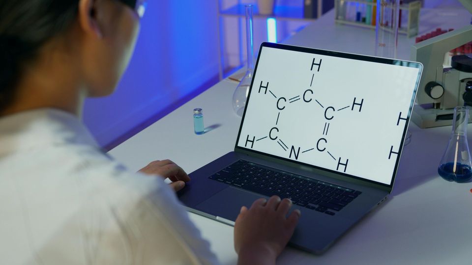 Researcher analyzing a molecular structure on a laptop in a laboratory.