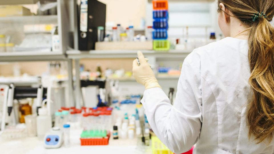 Researcher working in a laboratory with test tubes and equipment.