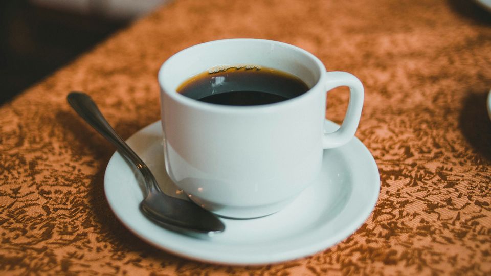 An espresso in a small white espresso cup and saucer.