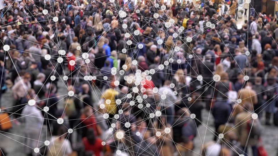 Large group of people standing on a pavement. A network of connecting white dots and lines is placed over the image.