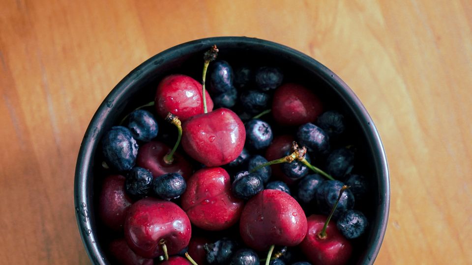 A bowl of washed ripe cherries and blueberries.