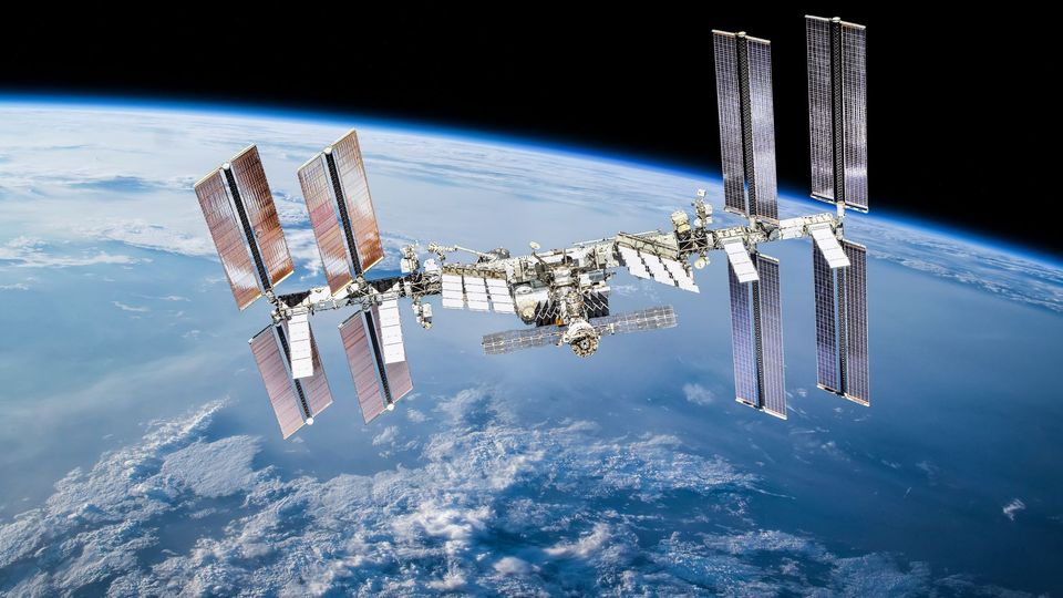 Space station orbiting Earth with panels extended on each side, against the backdrop of Earth.