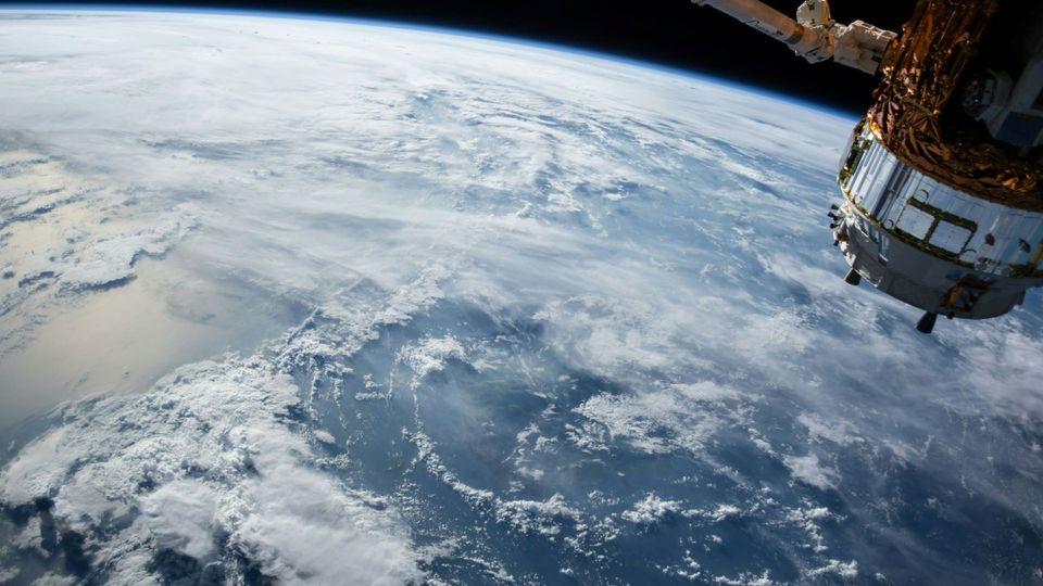 Satellite orbiting Earth above cloud-covered oceans.