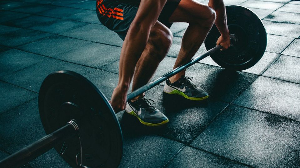 A man performing a barbell deadlift in a gym.